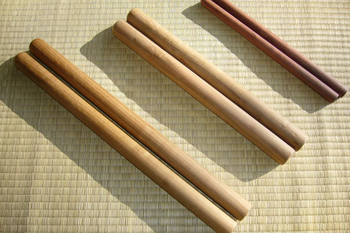 Three pairs of wooden taiko sticks of different thicknesses lie on a tatami mat